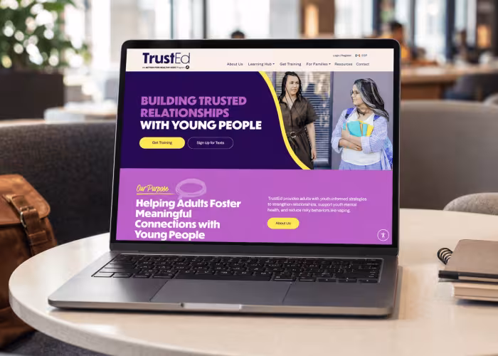 TrustEd website displayed on a laptop in a modern co-working lounge.